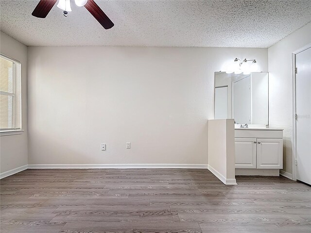 spare room featuring baseboards, wood finished floors, ceiling fan, and a textured ceiling
