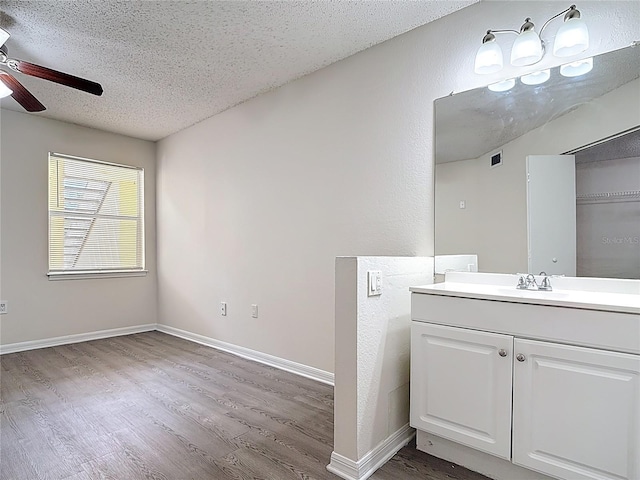 bathroom featuring a textured ceiling, visible vents, ceiling fan, wood finished floors, and vanity