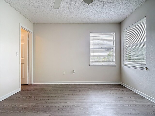 empty room featuring a textured ceiling, baseboards, wood finished floors, and a ceiling fan