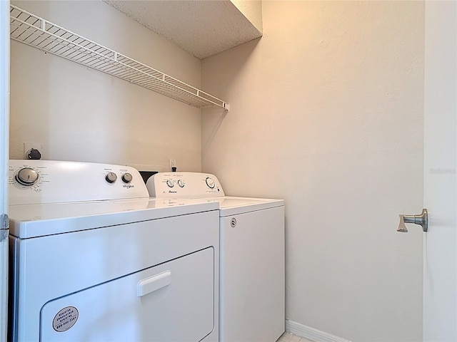 washroom with baseboards, washing machine and dryer, and laundry area