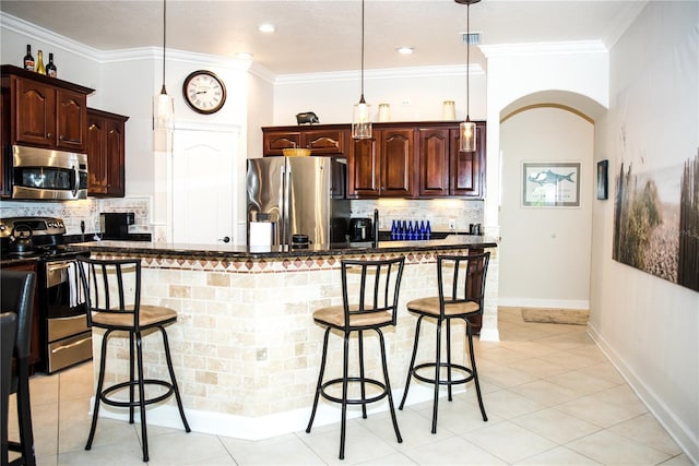 kitchen featuring stainless steel appliances, tasteful backsplash, a breakfast bar, and ornamental molding