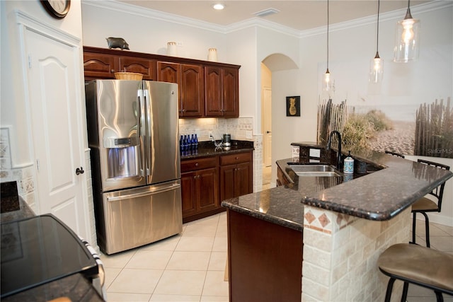 kitchen with a breakfast bar, light tile patterned flooring, stainless steel refrigerator with ice dispenser, decorative backsplash, and a sink