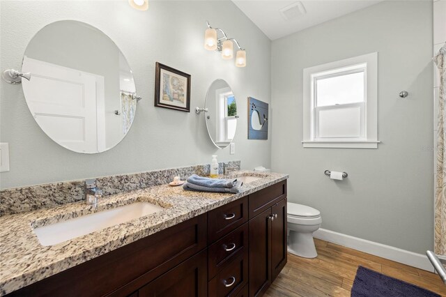 2623 57th St S, Gulfport, FL 33707 - full bathroom featuring a sink, toilet, wood finished floors, and baseboards