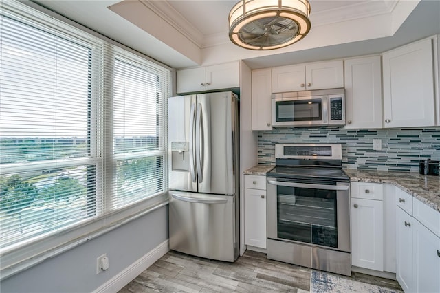 kitchen featuring crown molding, backsplash, white cabinets, a raised ceiling, and stainless steel appliances