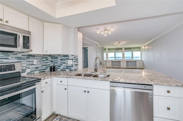 kitchen with crown molding, tasteful backsplash, white cabinets, appliances with stainless steel finishes, and a sink