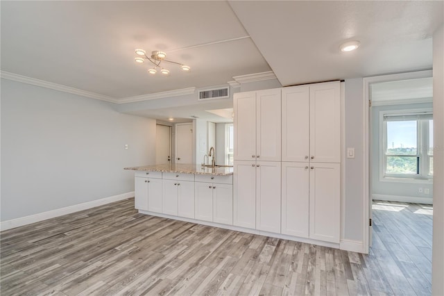 kitchen featuring white cabinets, visible vents, light wood-type flooring, and crown molding