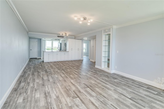 unfurnished living room with visible vents, ornamental molding, baseboards, and light wood-style floors