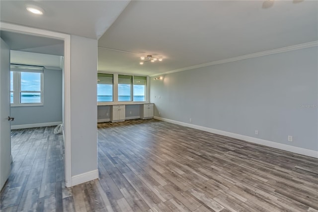 interior space featuring wood finished floors, baseboards, and ornamental molding