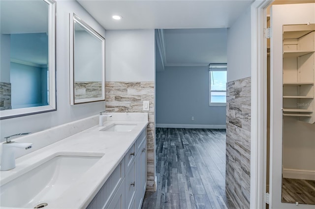 bathroom with wood finished floors, a sink, ornamental molding, and baseboards