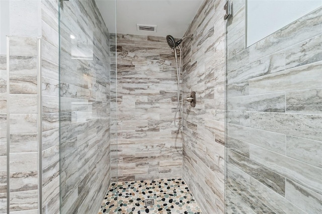 bathroom with visible vents and a tile shower
