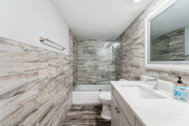 bathroom featuring vanity, toilet, tile walls, tub / shower combination, and wood finished floors