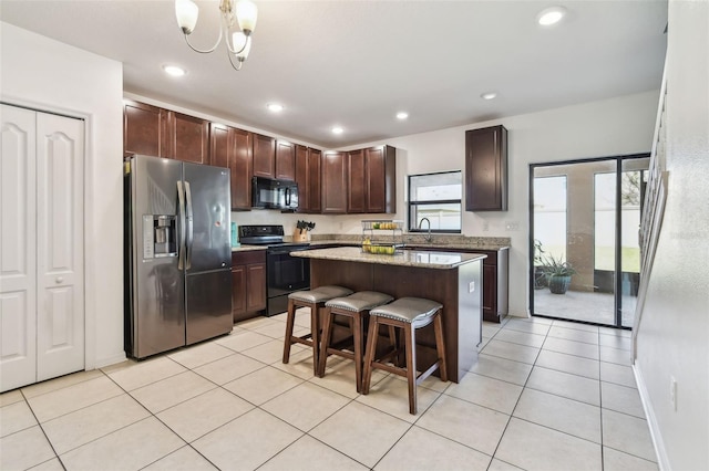 kitchen featuring a notable chandelier, light tile patterned flooring, black appliances, a kitchen island, and a sink