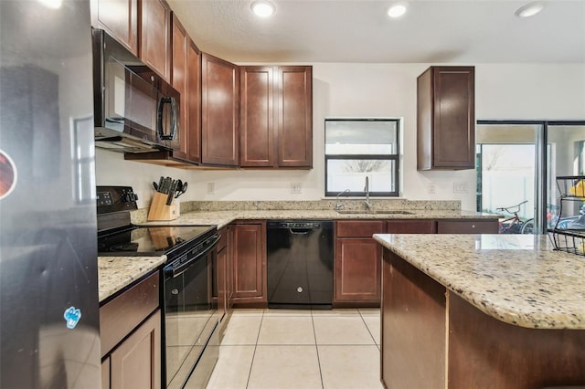 kitchen with light stone counters, recessed lighting, light tile patterned floors, black appliances, and a sink