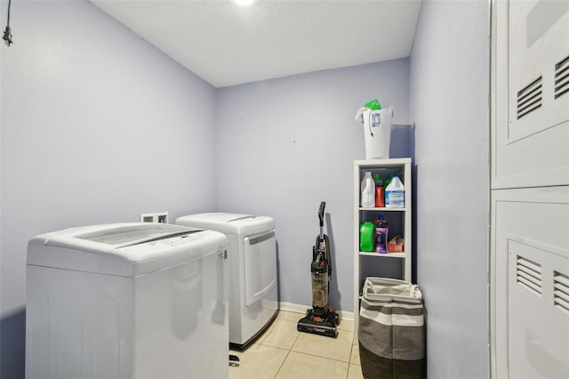 laundry area with laundry area, washing machine and clothes dryer, baseboards, and light tile patterned floors