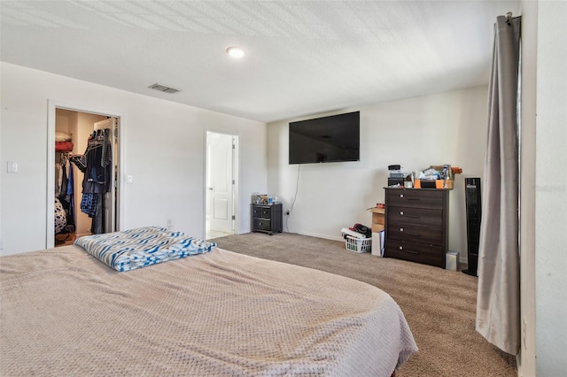 carpeted bedroom featuring visible vents, a spacious closet, and connected bathroom