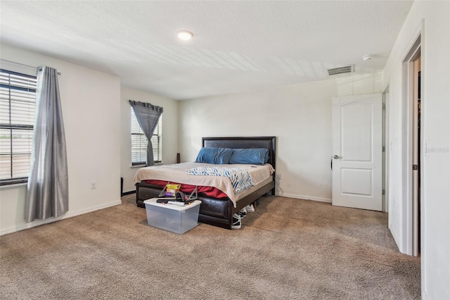 bedroom featuring visible vents, a textured ceiling, baseboards, and carpet floors