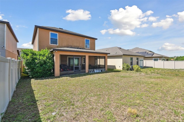 back of property with a fenced backyard, a sunroom, and a lawn