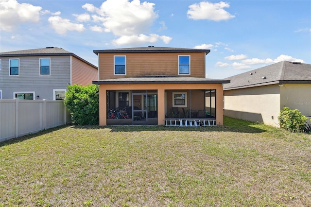 rear view of house with fence, a sunroom, and a lawn