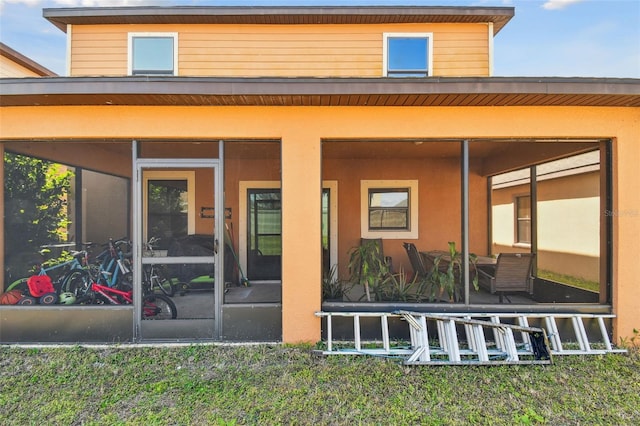 rear view of house with a sunroom and stucco siding