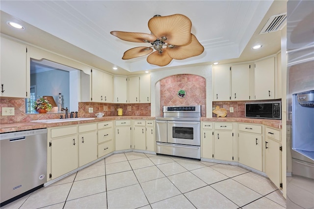 6589 Banyan Dr, Indian Lake Estates, FL 33855 - kitchen with visible vents, a sink, a tray ceiling, stainless steel appliances, and cream cabinets