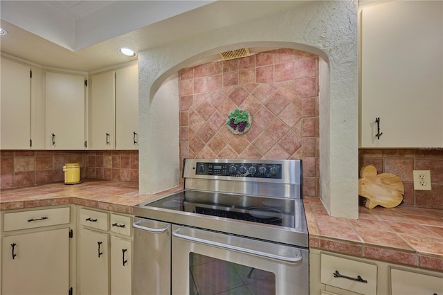 6589 Banyan Dr, Indian Lake Estates, FL 33855 - kitchen featuring backsplash, range with two ovens, and cream cabinetry