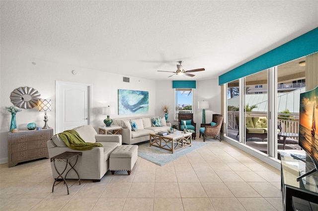 living area featuring ceiling fan, light tile patterned floors, and a textured ceiling