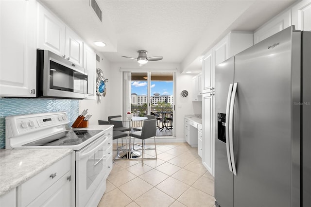 kitchen with appliances with stainless steel finishes, white cabinetry, a ceiling fan, backsplash, and light tile patterned flooring