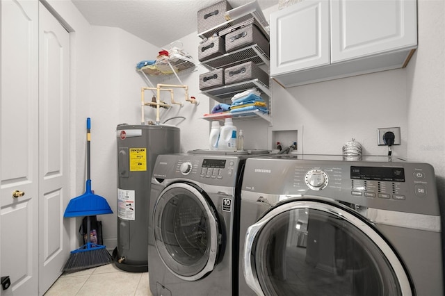 clothes washing area featuring cabinet space, water heater, washing machine and dryer, and light tile patterned floors