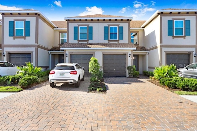 multi unit property featuring driveway, stucco siding, and an attached garage