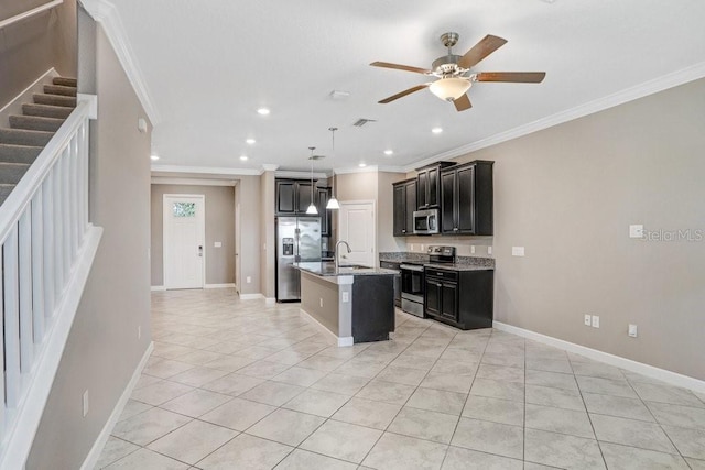 kitchen with light tile patterned flooring, an island with sink, a ceiling fan, appliances with stainless steel finishes, and dark cabinets