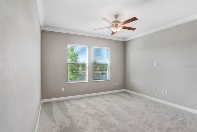 carpeted spare room featuring ornamental molding, baseboards, and ceiling fan