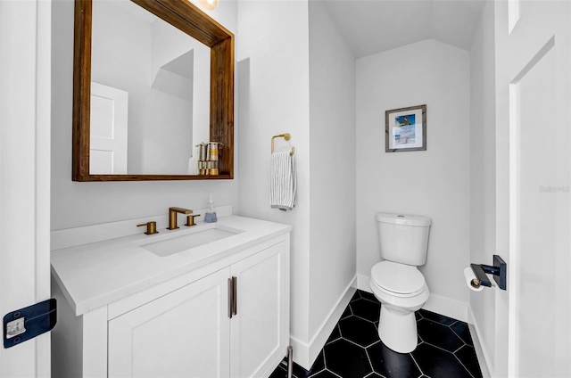bathroom with vanity, toilet, lofted ceiling, tile patterned floors, and baseboards