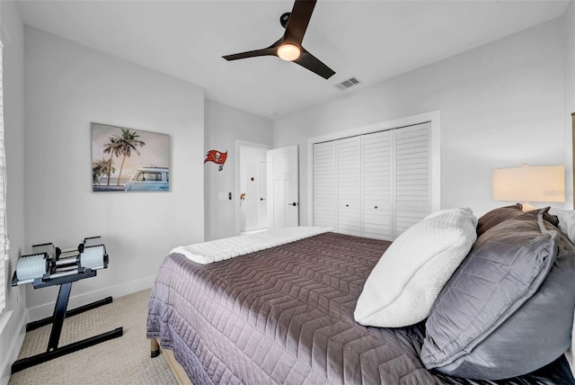 carpeted bedroom with a closet, visible vents, baseboards, and a ceiling fan