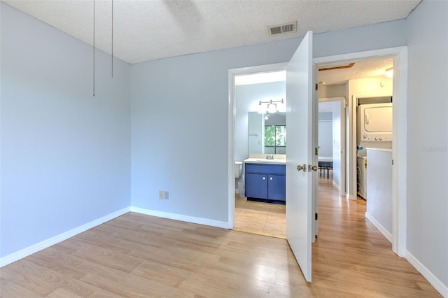 1424 Highland Ridge Cir, Brandon, FL 33510 - unfurnished bedroom with visible vents, baseboards, a textured ceiling, stacked washer and dryer, and light wood finished floors