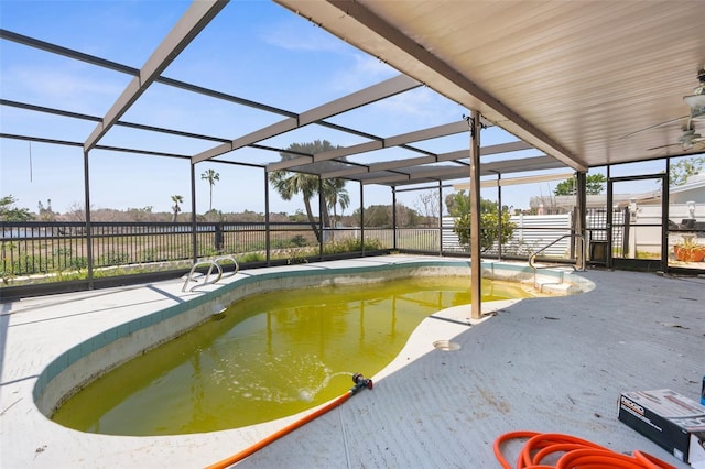 pool with fence, a patio, ceiling fan, and glass enclosure