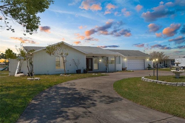 single story home featuring curved driveway, an attached garage, and a lawn