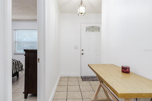 entrance foyer featuring a textured ceiling, baseboards, and light tile patterned floors