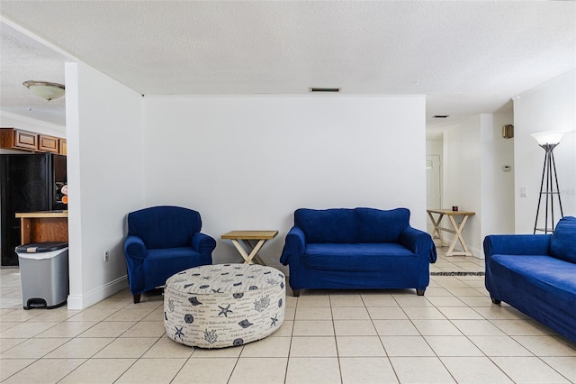 sitting room with baseboards, a textured ceiling, visible vents, and light tile patterned floors
