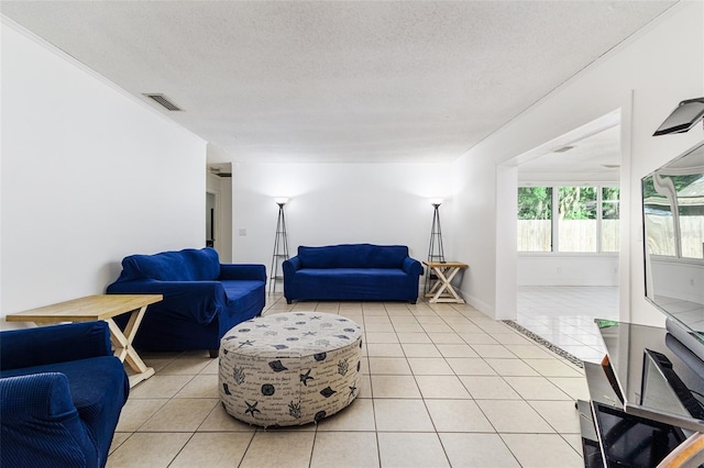 living area featuring baseboards, a textured ceiling, visible vents, and light tile patterned floors