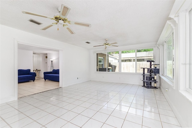 unfurnished room with a textured ceiling, visible vents, a wood stove, and light tile patterned floors