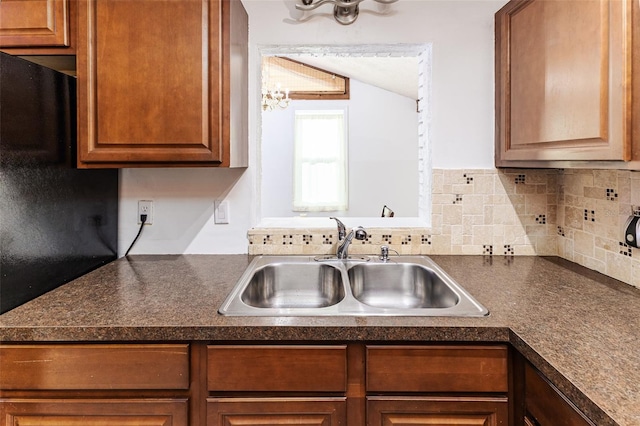 kitchen with vaulted ceiling, backsplash, a chandelier, a sink, and dark countertops