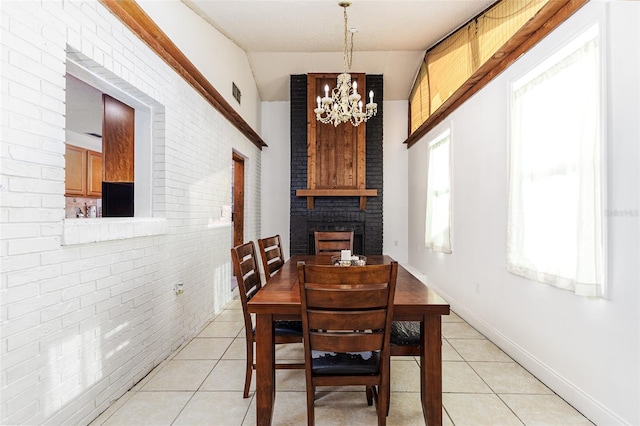 dining room featuring baseboards, a chandelier, light tile patterned floors, and brick wall