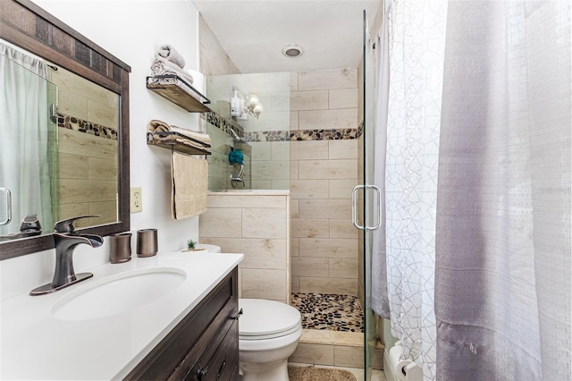 full bath featuring toilet, vanity, and a stall shower