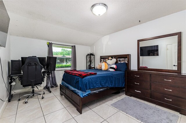 bedroom featuring light tile patterned flooring, lofted ceiling, and a textured ceiling