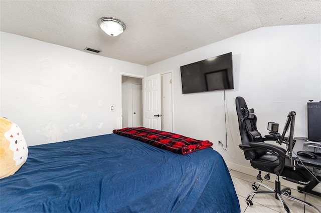 bedroom featuring light tile patterned flooring, vaulted ceiling, visible vents, and a textured ceiling