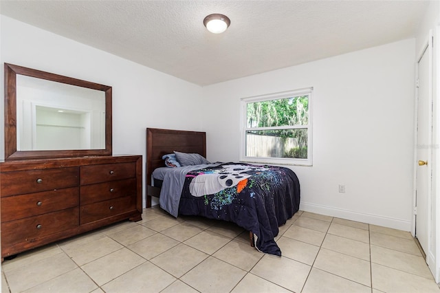 bedroom with light tile patterned floors, baseboards, and a textured ceiling