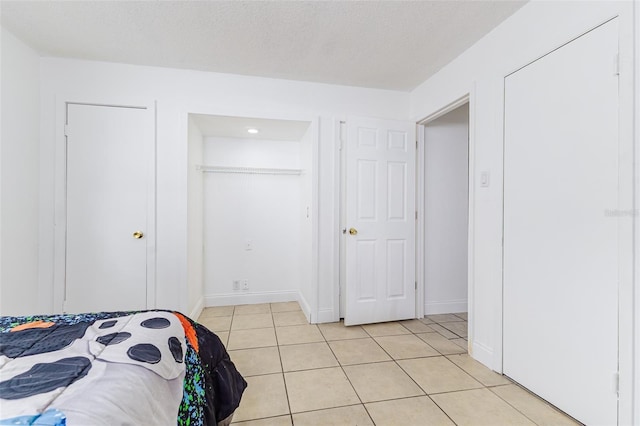 bedroom with light tile patterned flooring, baseboards, and a textured ceiling