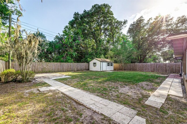 view of yard featuring a storage unit, a fenced backyard, and an outdoor structure