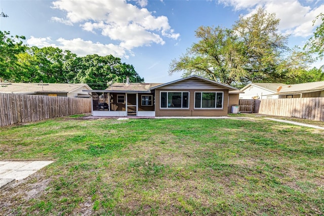 rear view of house featuring a fenced backyard, a sunroom, and a yard