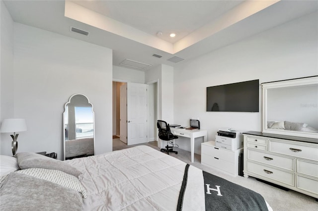 bedroom featuring a raised ceiling, attic access, light colored carpet, and visible vents